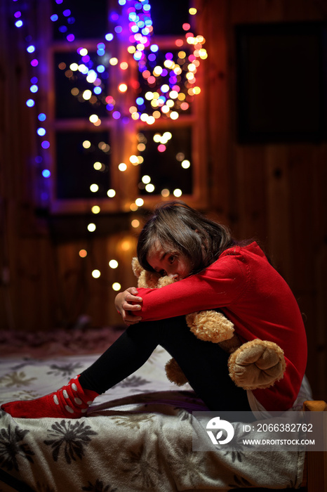 sad and tearful girl sitting with a teddy bear