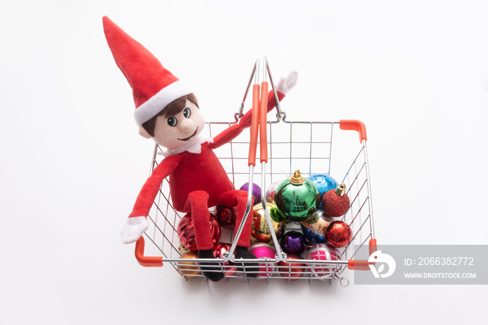 Toy elf in shopping basket with baubles