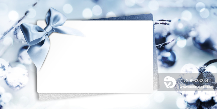 gift or greeting card with blue ribbon bow on blurred blue christmas background, white copy space