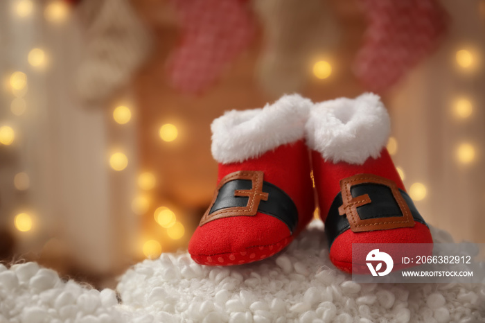 Christmas baby booties on fluffy fabric against blurred background