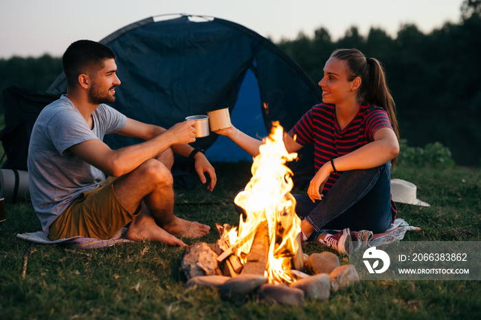 romantic couple on camping by the river outdoors by the camping fire