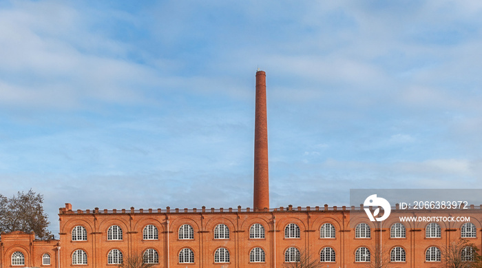 Old factory in orange brick with giant chimney.