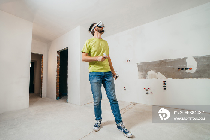 Young bearded man using virtual reality goggles before starting renovations in his townhouse