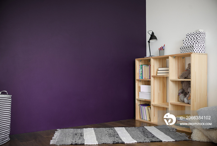 Loft interior with a woden bookcase with book and children toy and rug on wood floor and violet wall