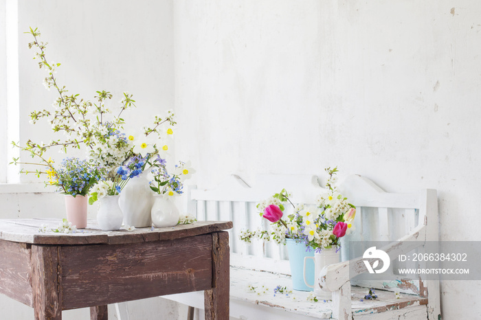 spring flowers in vintage white interior with old wooden bench