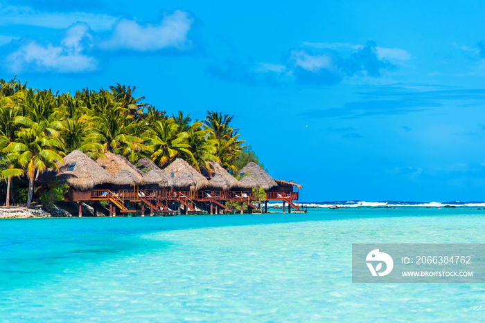 Stunning tropical Aitutaki island with palm trees, water bungalow, white sand, turquoise ocean water