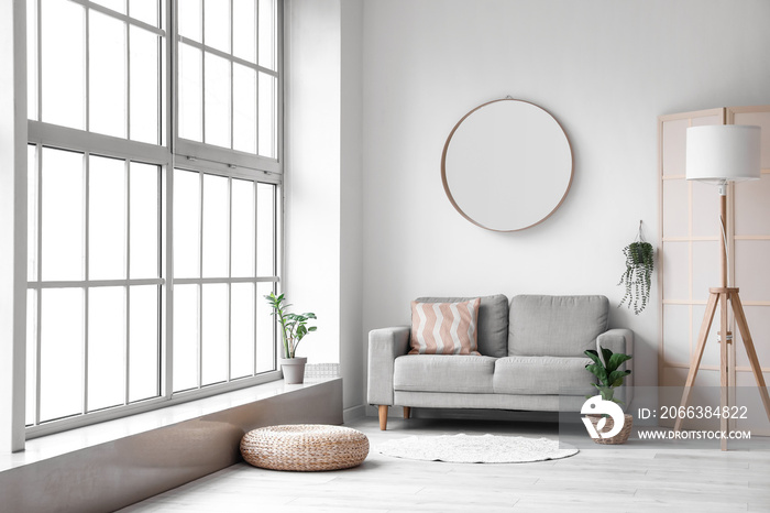 Interior of modern room with comfortable sofa, mirror and lamp