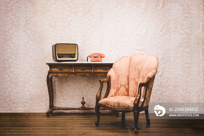 Old telephone, radio and armchair in an interior place with retro style decoration.