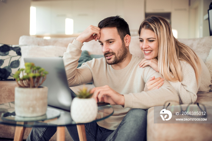 Beautiful young couple is using a laptop at home