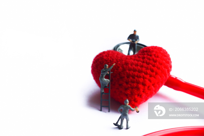 Tiny model take care red heart model near the red stethoscope on isolated background