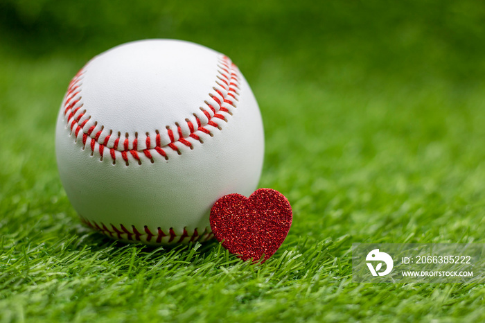 Baseball with red heart are on green grass with love for Valentines Day