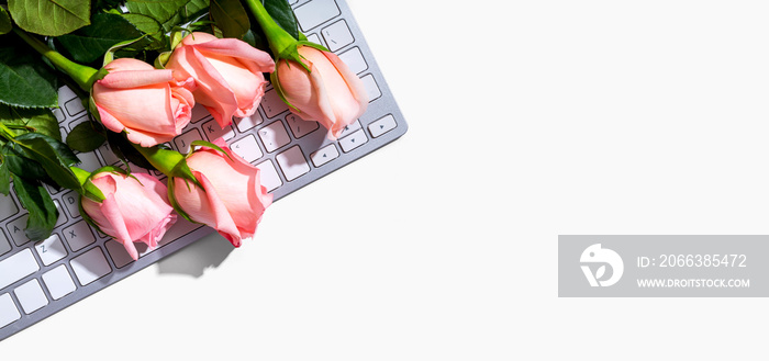 Computer keyboard with pink roses - flat lay