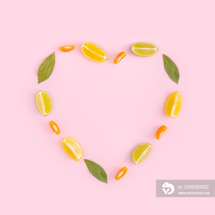 Creative minimal fruit concept with heart shape made of citrus fruits and green leaves on pastel pin