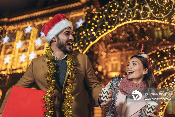 Young romantic couple holding gift box having fun outdoors in winter before Christmas.