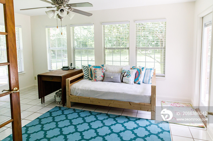 Boho Bohemian style futon seating area with white cushions and colorful pillows and lots of windows 