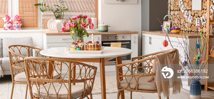 Tray with Easter cakes, eggs and vase with tulips on dining table in kitchen