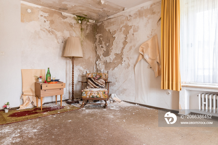 Room in a run-down hotel with a chair next to a cabinet with clutter