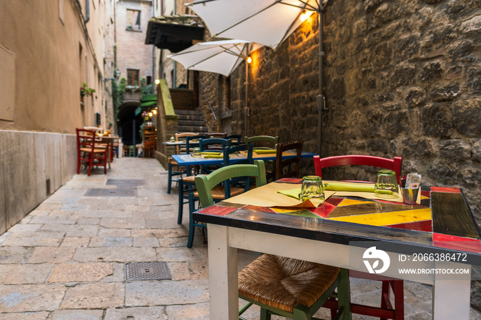 Tables and chairs in a narrow alley, trattoria in Italy