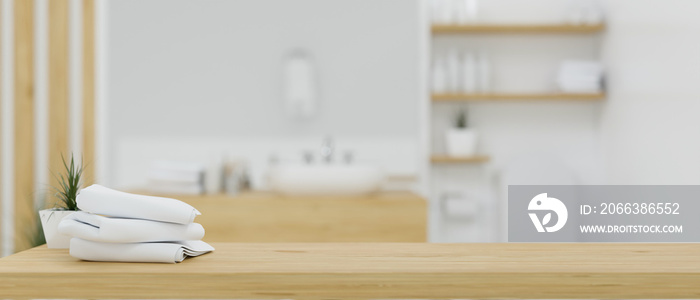 Wooden table top with bath towels over blurred white and wood minimalist bathroom