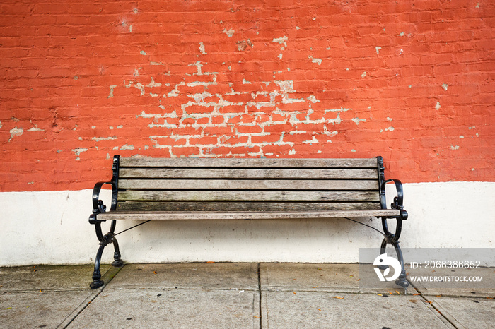 Old wooden bench on in front of a red brick wall on a sideway in a small American town; copy space