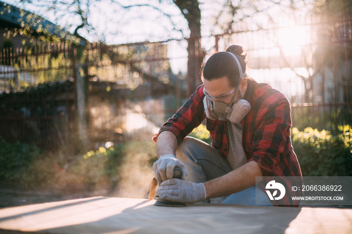 A male carpenter works with a wood grinder. Professional equipment and protective equipment.