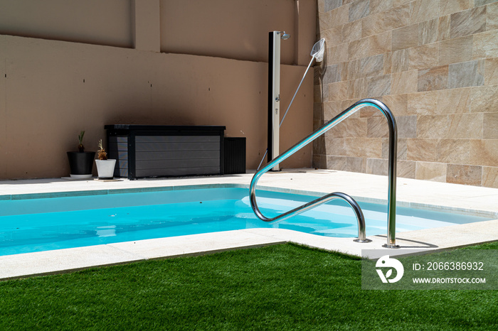 Swimming pool with artificial grass, a handrail with stairs, a shower and a cabinet for the purifier
