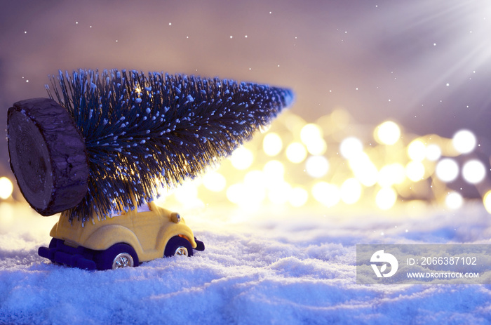 Christmas tree on toy car in winter on snow at night. Christmas holiday celebration concept