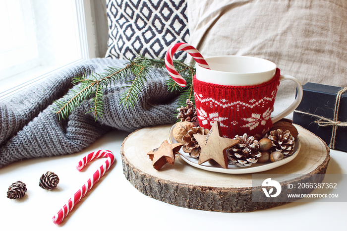 Winter morning breakfast still life scene. Cup of coffee, tea with candy canes standing near window 