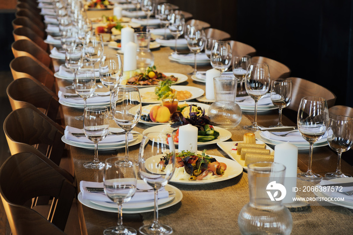 Glasses, forks, knives, plates on a wooden table in restaurant served for holiday. Festive table set