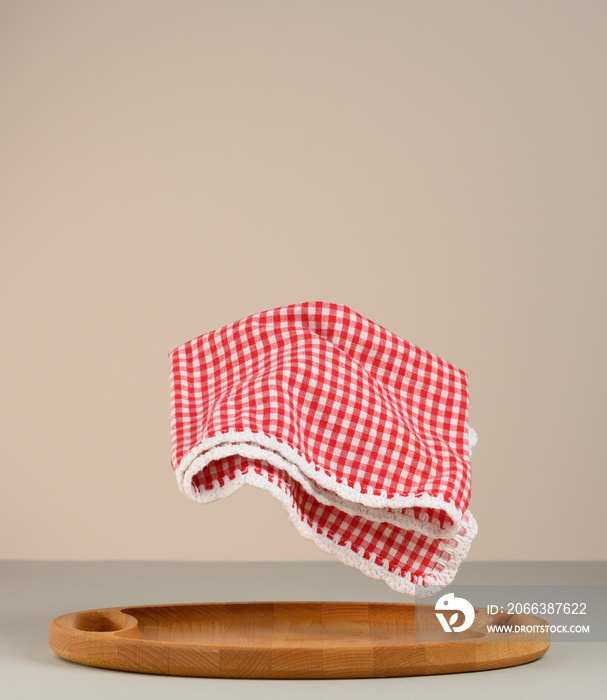 red and white checked kitchen towel levitates over kitchen wood board
