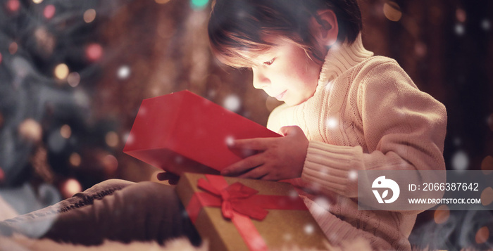 Family on Christmas eve at fireplace. Kids opening Xmas presents. Children under Christmas tree with