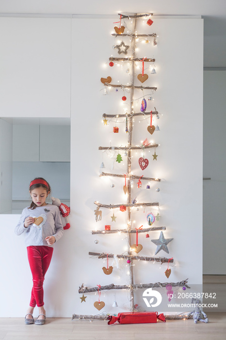 Little girl standing by a unique Christmas tree