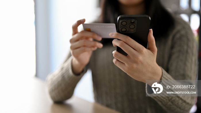 Cropped image an Asian woman holding a smartphone and a credit card. mobile banking