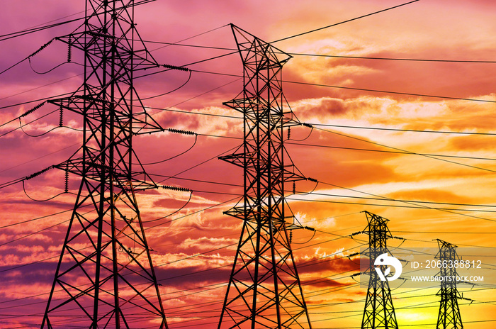 High voltage power lines and pylon towers in a bright sunset