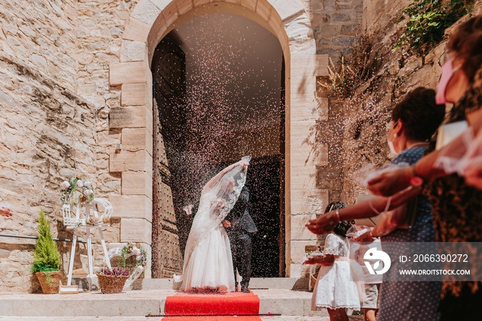 Novios saliendo de la iglesia. Gente tirando arroz en boda. Momento del arroz en una boda. Recién casados. Esposos.