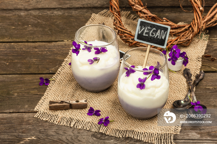 Vegan panna cotta dessert with fresh violet flower. Striped very peri color food, rustic style