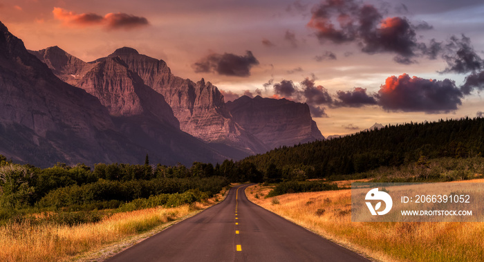 Beautiful View of Scenic Highway with American Rocky Mountain Landscape in the background. Colorful Summer Sunrise Sky. Taken in St Mary, Montana, United States.