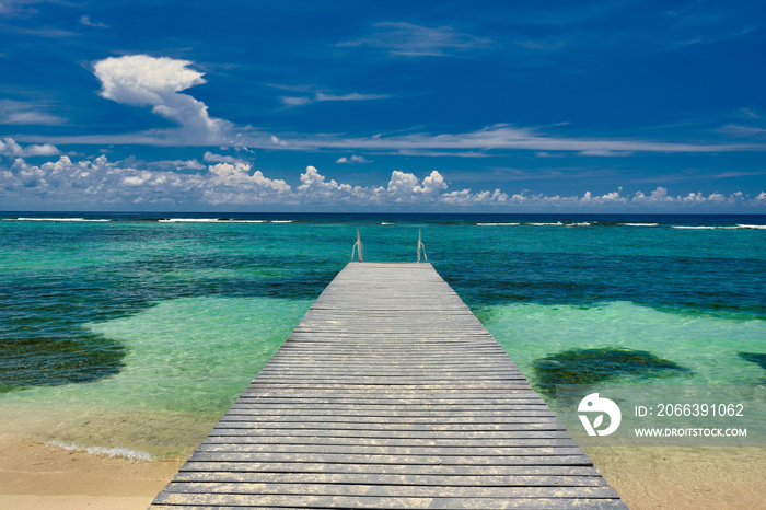 A beautiful wood dock leads out to the crystal clear and turquoise waters of the Cayman Islands in the tropical Britsh west indies