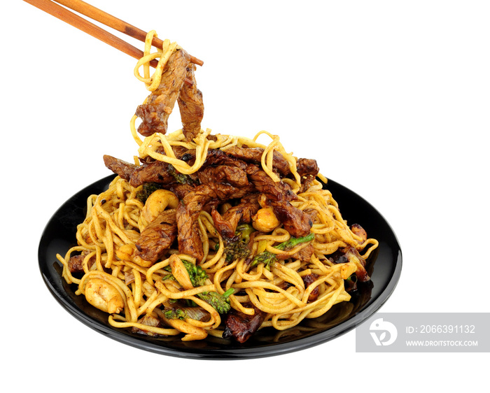 Beef in black bean sauce with egg noodles and cashew nuts meal with wood chopsticks isolated on a white background
