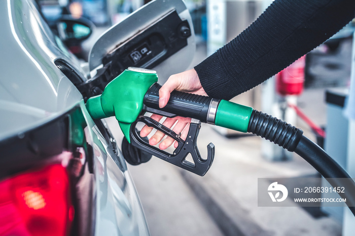 Woman pumping gasoline fuel in car at gas station.