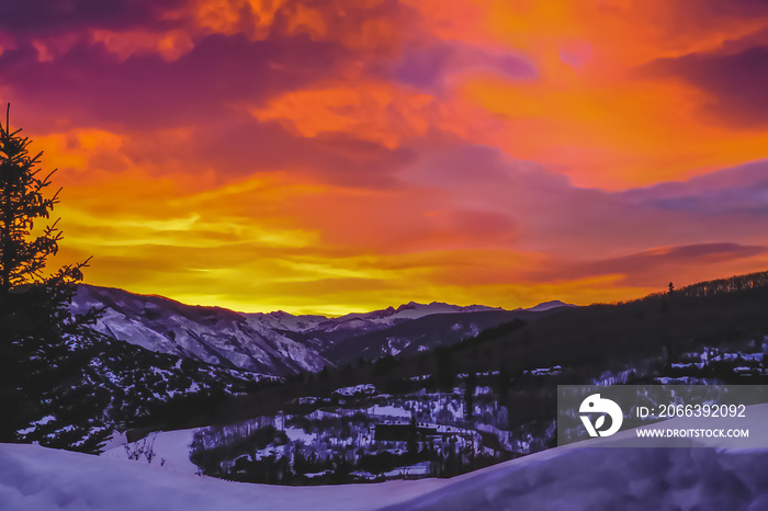 View of sunrise in Colorado Rocky Mountains as seen from the window in ski village near Aspen; sun peeking through the clouds