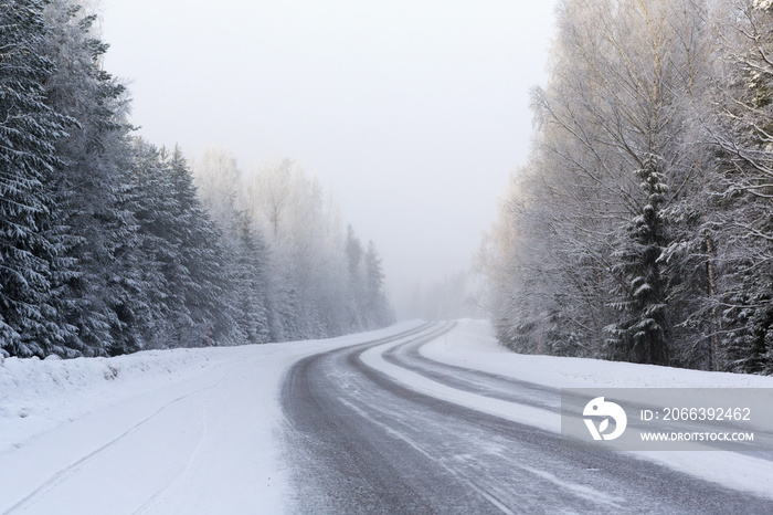 Winding and wintry road in Finland. Curves with snow covered asphalt road. Empty highway for traveling.