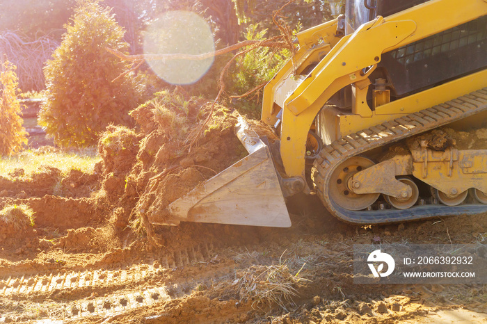 Mini bulldozer working with earth soil while doing landscaping works on construction