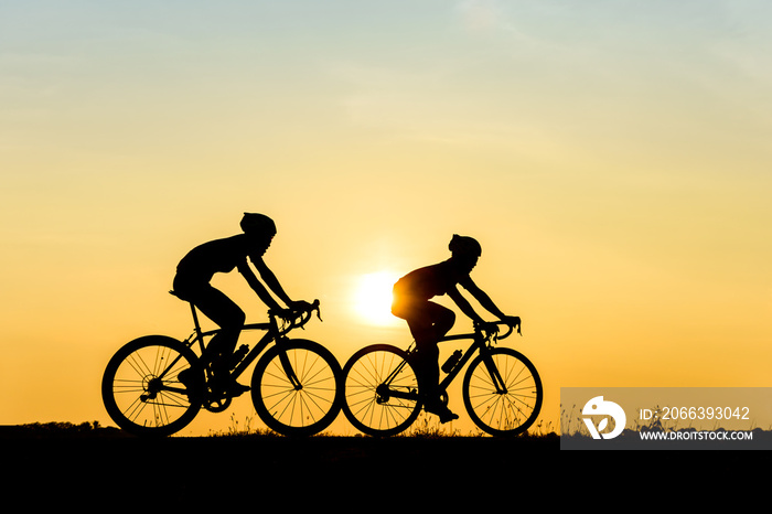 Silhouette of cyclist with friend motion on sunset background