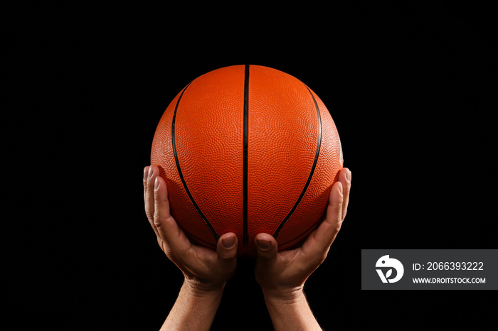 Hands of basketball player with ball on dark background