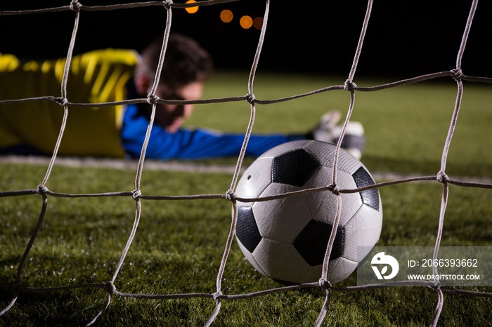 Close-up of soccer ball in goal post against goalkeeper