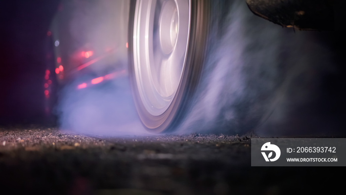 Drag racing car burning tire at starting line in race track