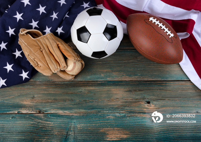US flag with soccer ball, baseball and football on faded blue wooden planks for sport concept