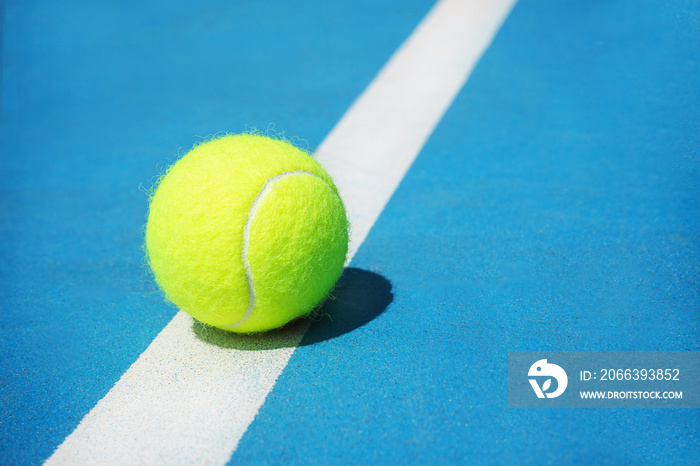 Summer sport concept with tennis ball on white line on hard tennis court. Flat lay, top view, copy space, close up. Blue and green.