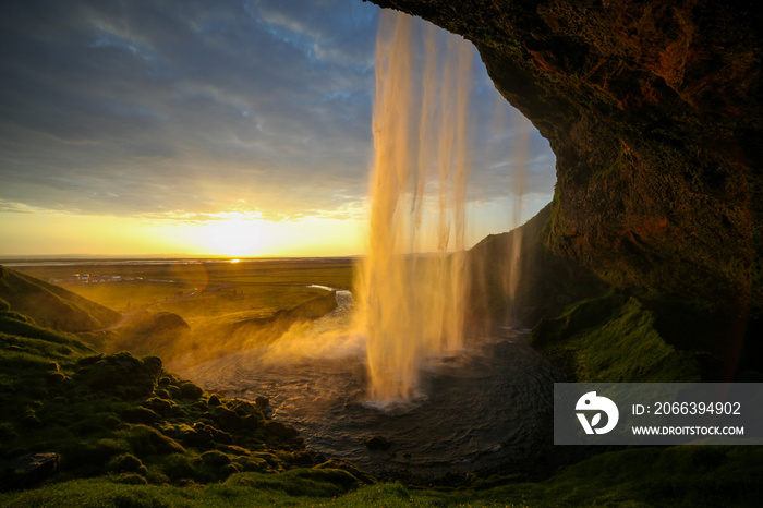 Waterfall Selandjafoss Iceland at sunset or sunrise. Beautiful waterfall in Iceland. Golden hour. Cave and waterfall. Travel in Iceland. Beautiful sky against the big waterfall. inside the water.